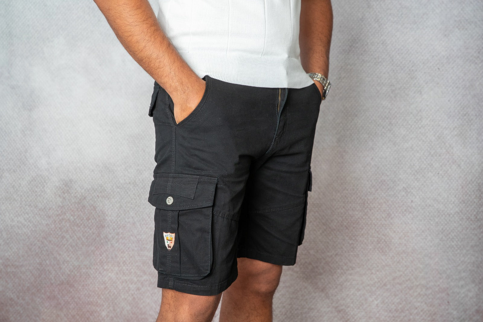 Pantaloncini cargo uomo Bolgi neri a vita media con tasche laterali e logo ricamato, indossati in look estivo casual.