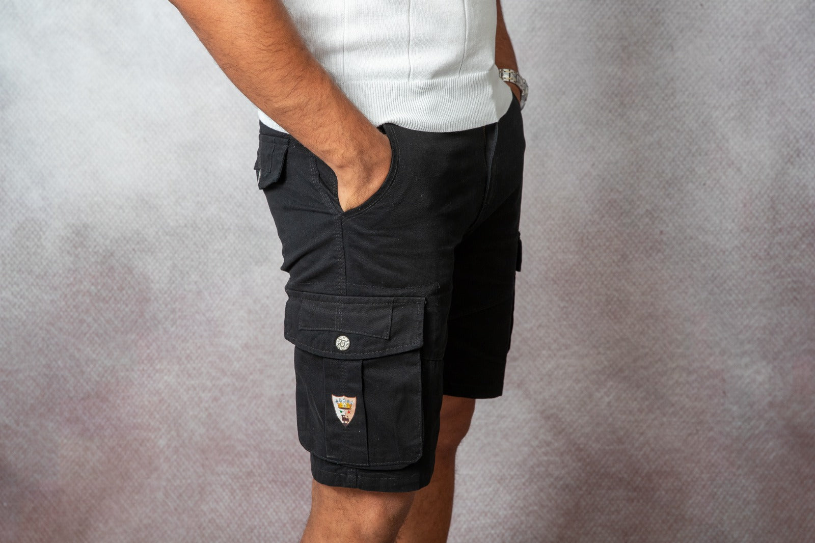 Pantaloncini cargo uomo Bolgi neri a vita media con tasche laterali e logo ricamato, indossati in look estivo casual.